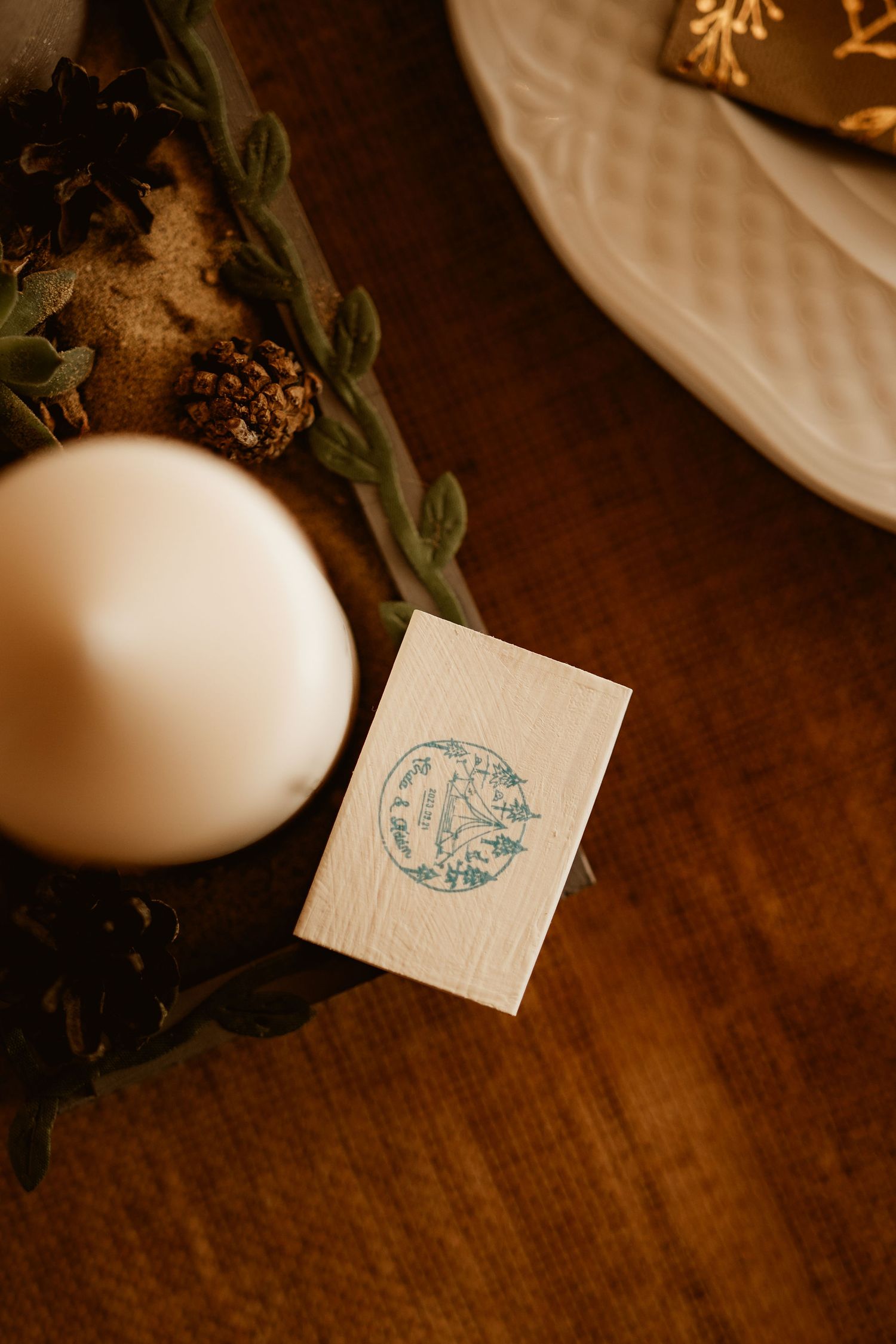 Small white card with blue design and candle on dark wooden surface.