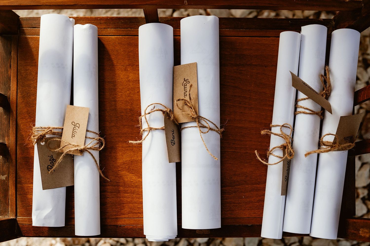 White rolled documents tied with twine arranged in a wooden box.