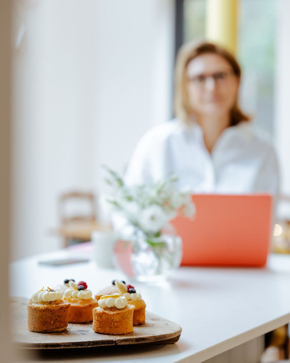 person at kitchen island with cakes working at laptop for branding photography at location in Kent