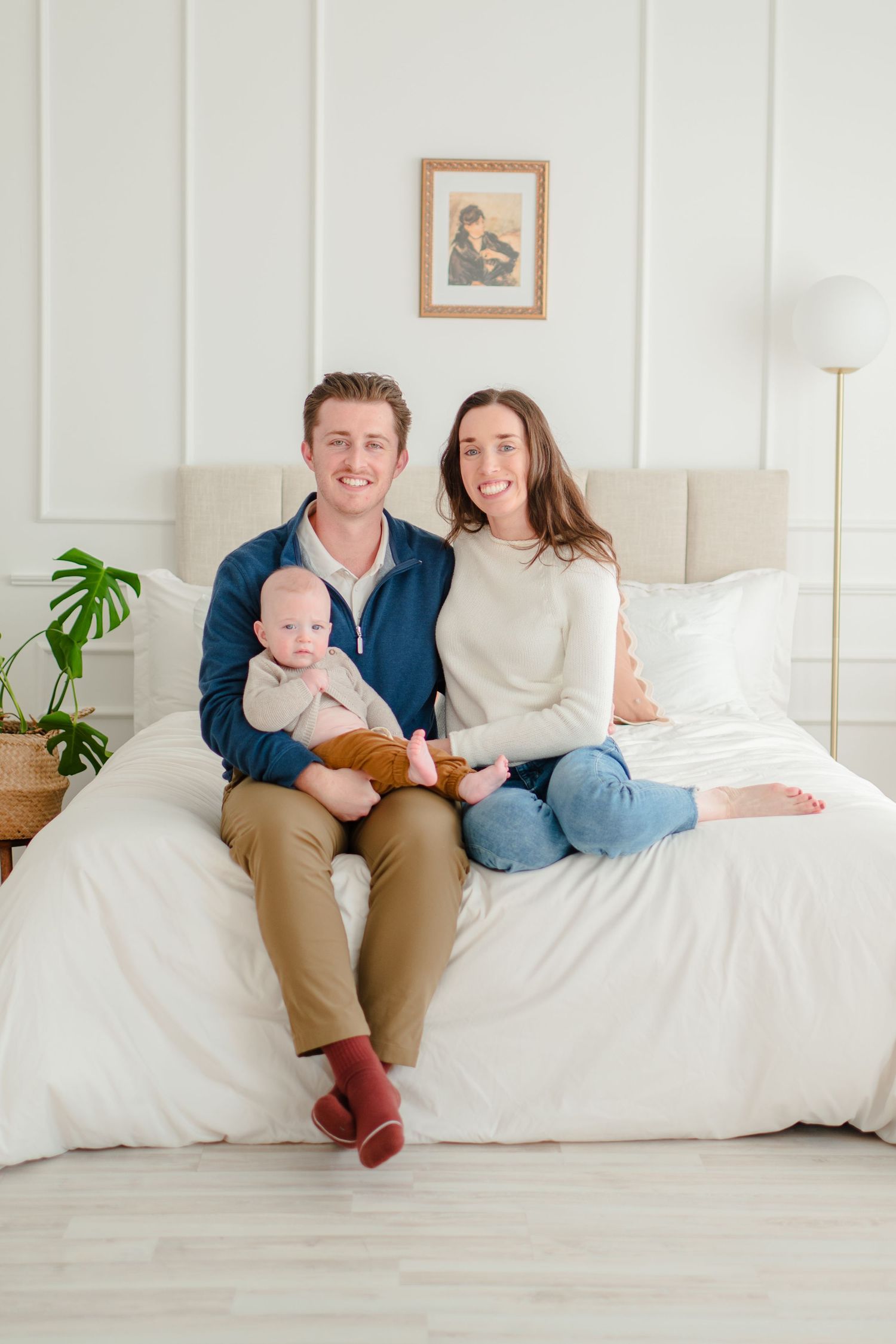 Modern family photo in minimalist home interior with white bedding and plant decor.