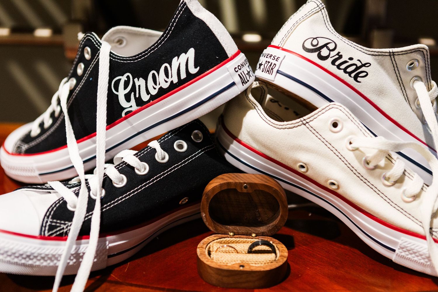 Customized bride and groom Converse sneakers with wedding rings in wooden box.