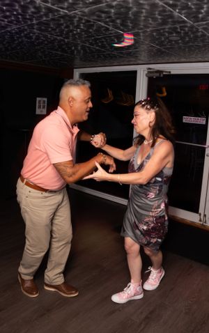 Two people dancing energetically together on a dark dance floor.