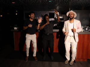 Dancers in white outfits moving on a dark dance floor at a party.
