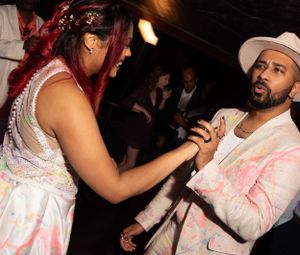 Party scene with dancers in white clothing performing under dramatic lighting.