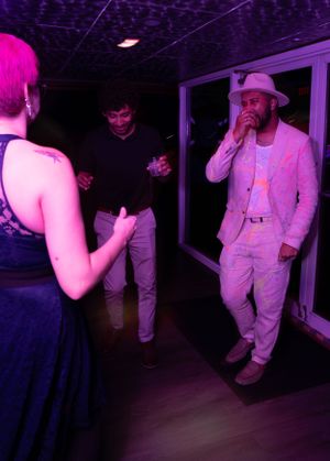 Dancers moving energetically in a dark nightclub under pink and purple lighting.