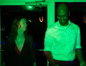 People dancing under bright green lighting at a nightclub party.