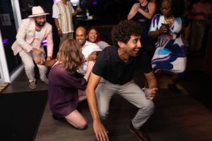 Party guests dancing and celebrating on a dark dance floor with colored lights.