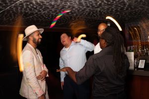 Party goers socializing and dancing under colorful lights at a nighttime event.