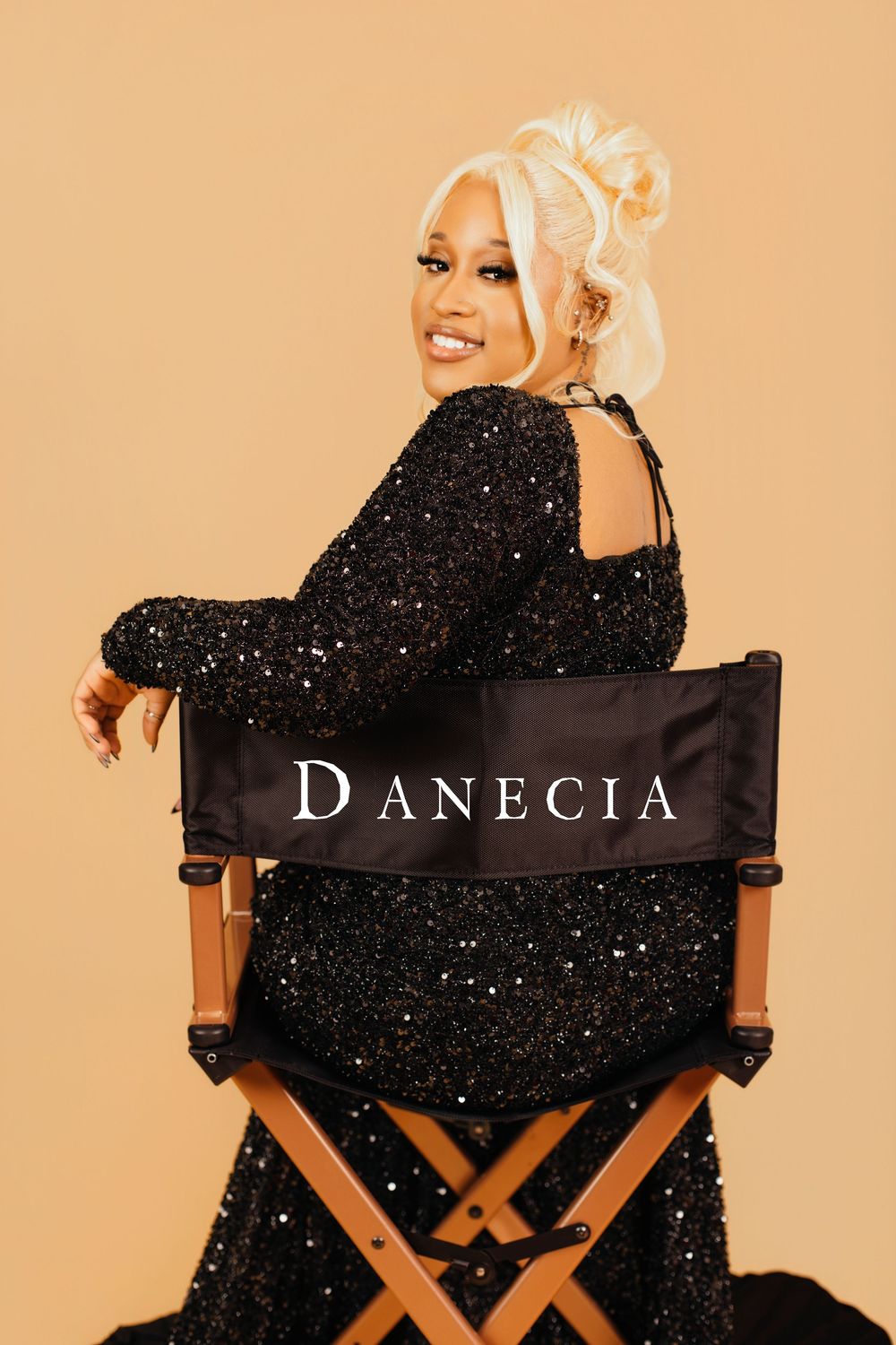 Director's chair with Danecia text against peach background in studio setting.