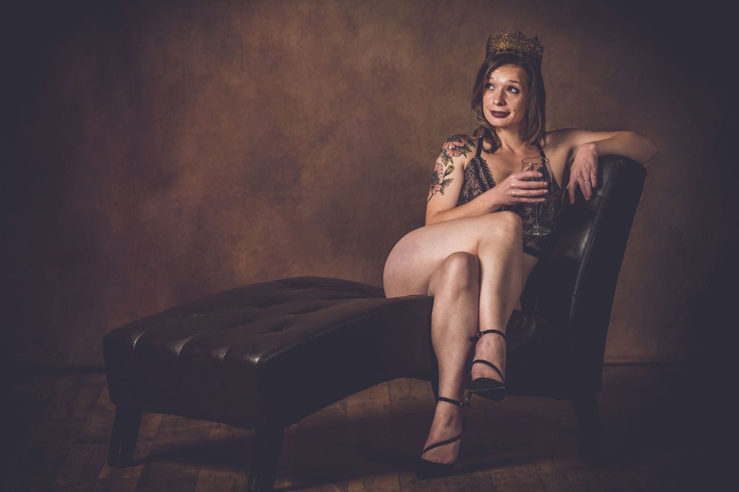 Vintage-style portrait on leather chaise lounge with moody brown backdrop. bridal boudoir