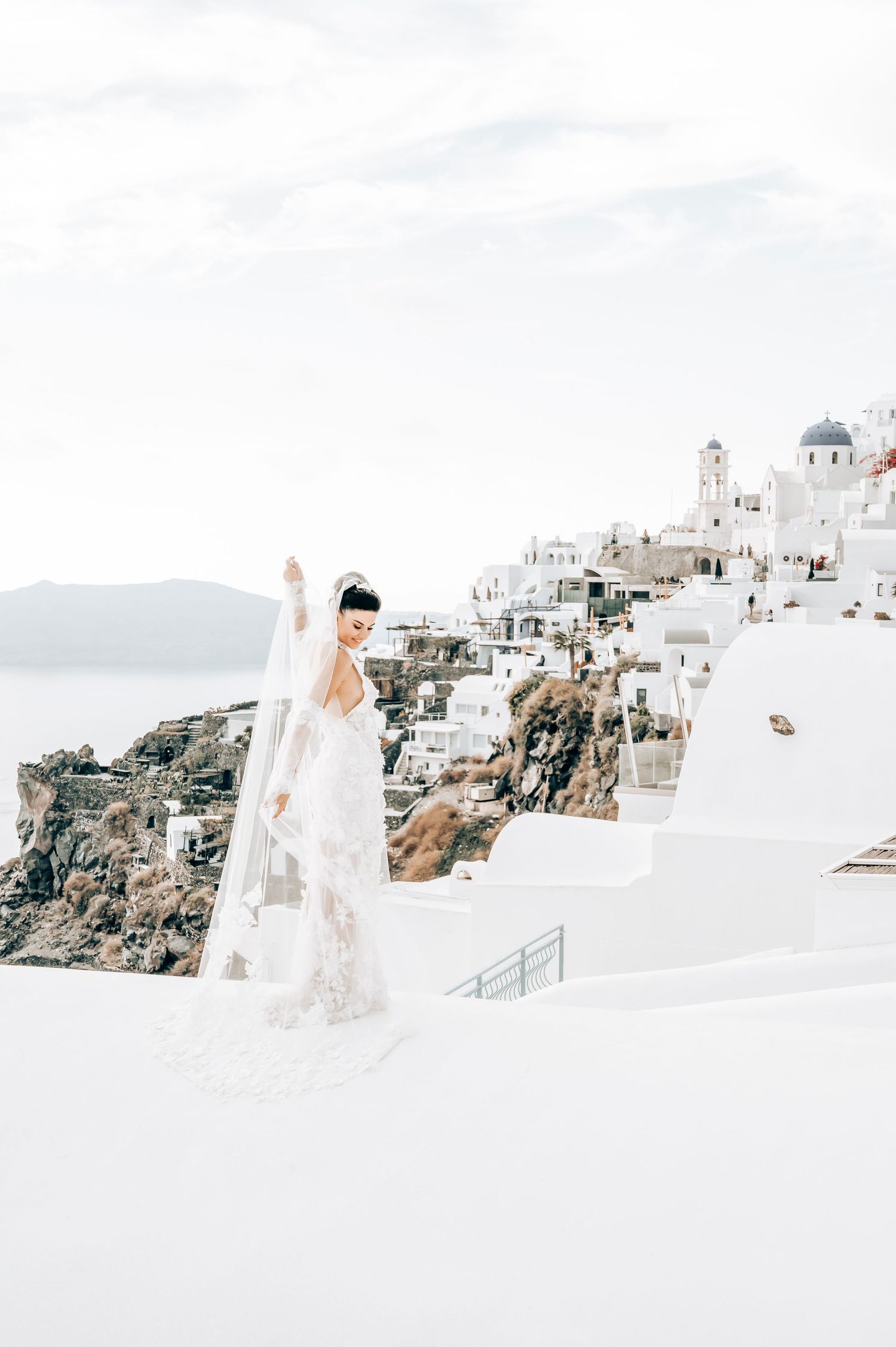Wedding photography showcasing a lace gown against Santorini's dramatic coastal landscape.