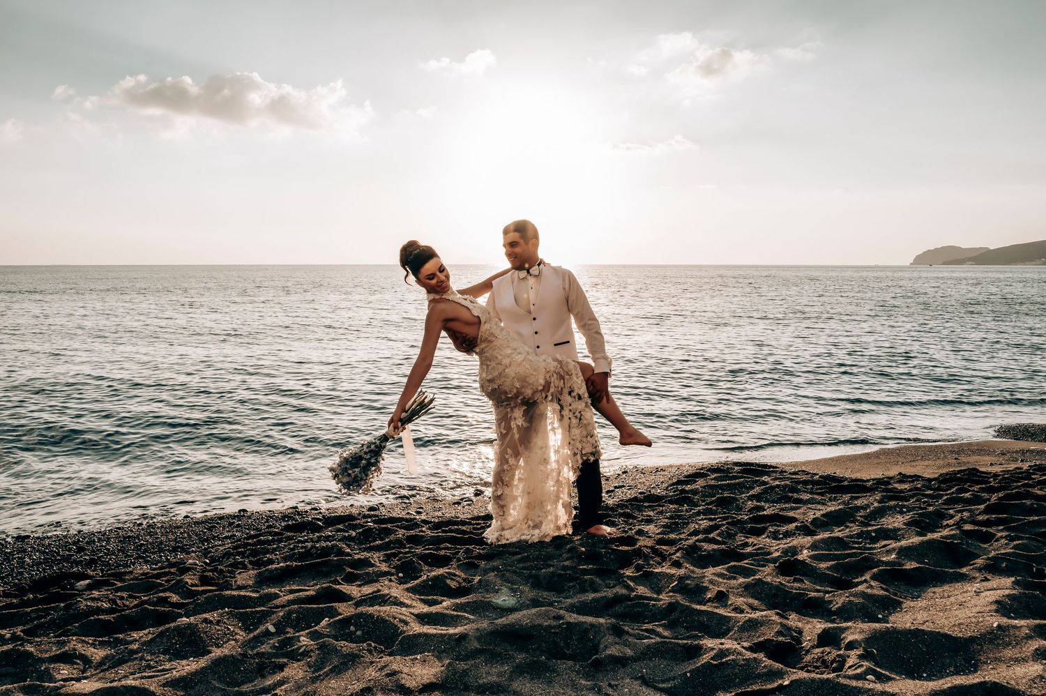 Dancing newlyweds on black sand beach at golden hour.