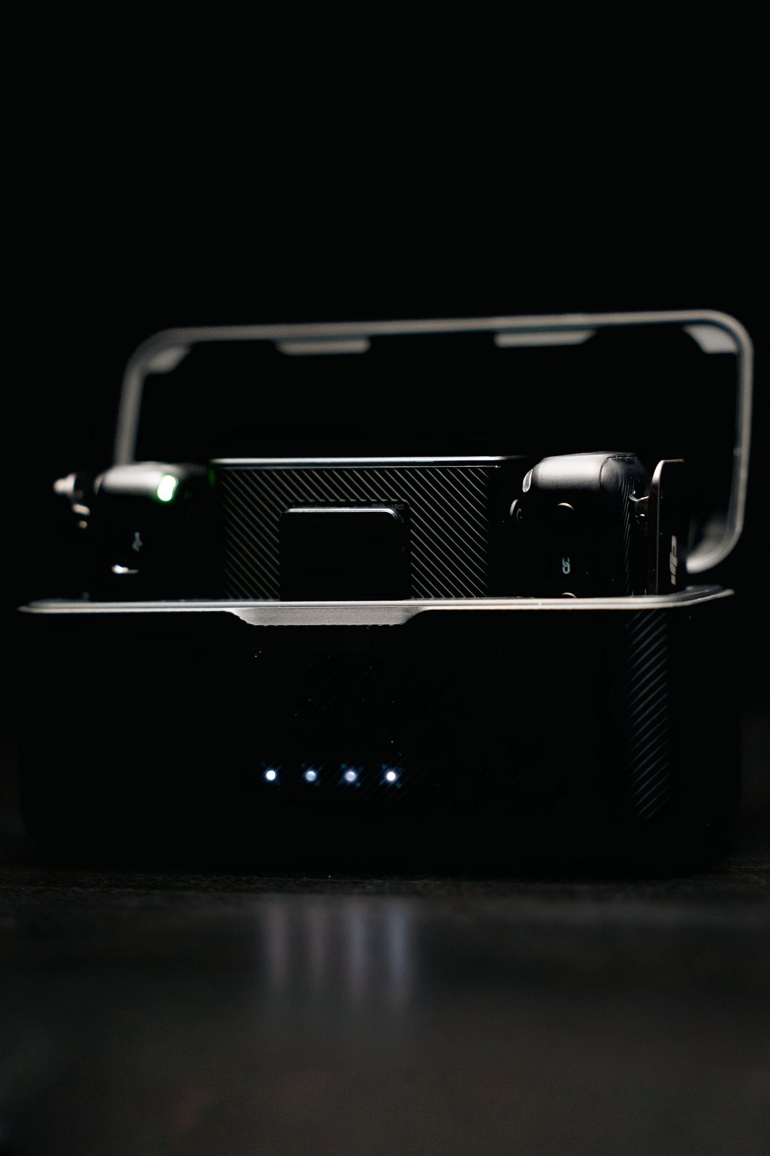 Low-key photo of wireless transmitters in charging dock with blue status lights.