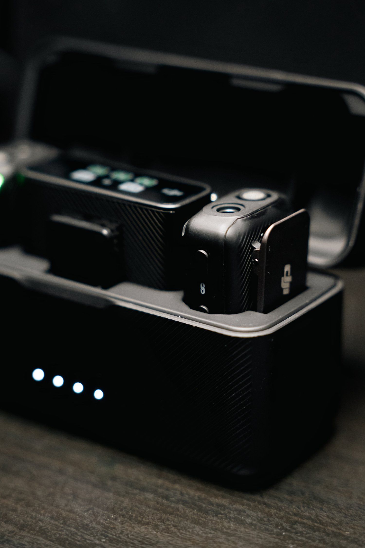 DJI wireless transmitters in charging case with LED indicators visible.