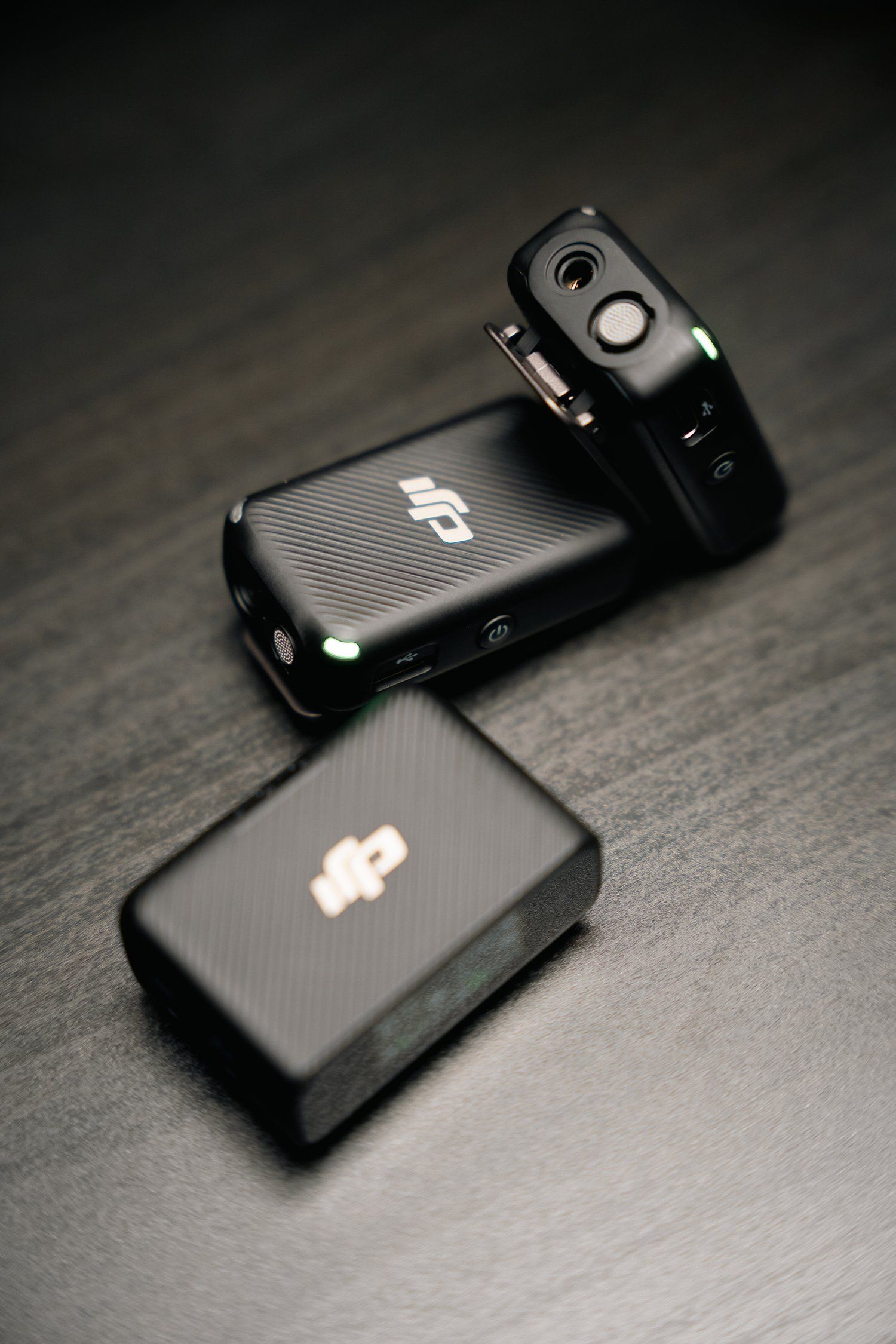 Two black DJI wireless transmitters with carbon fiber texture shown on dark surface.
