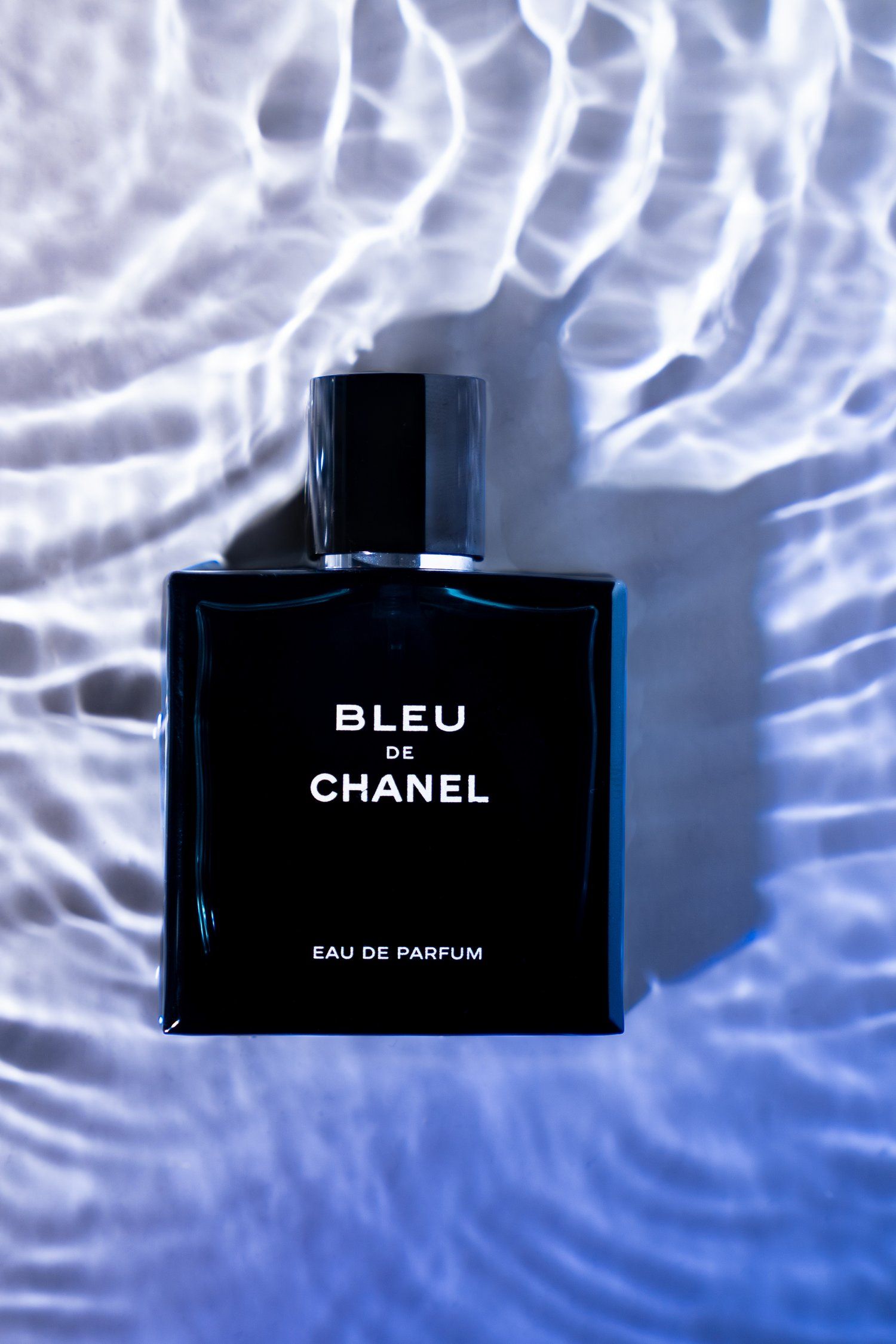 Chanel Bleu parfum bottle photographed against rippled water effect background.