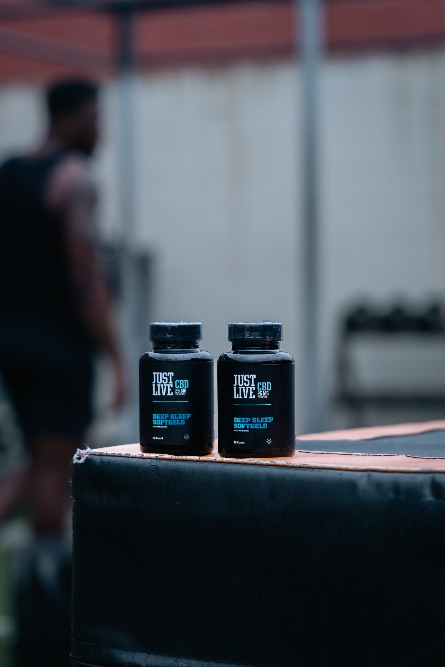 Two black supplement bottles on dark surface with blurred background.