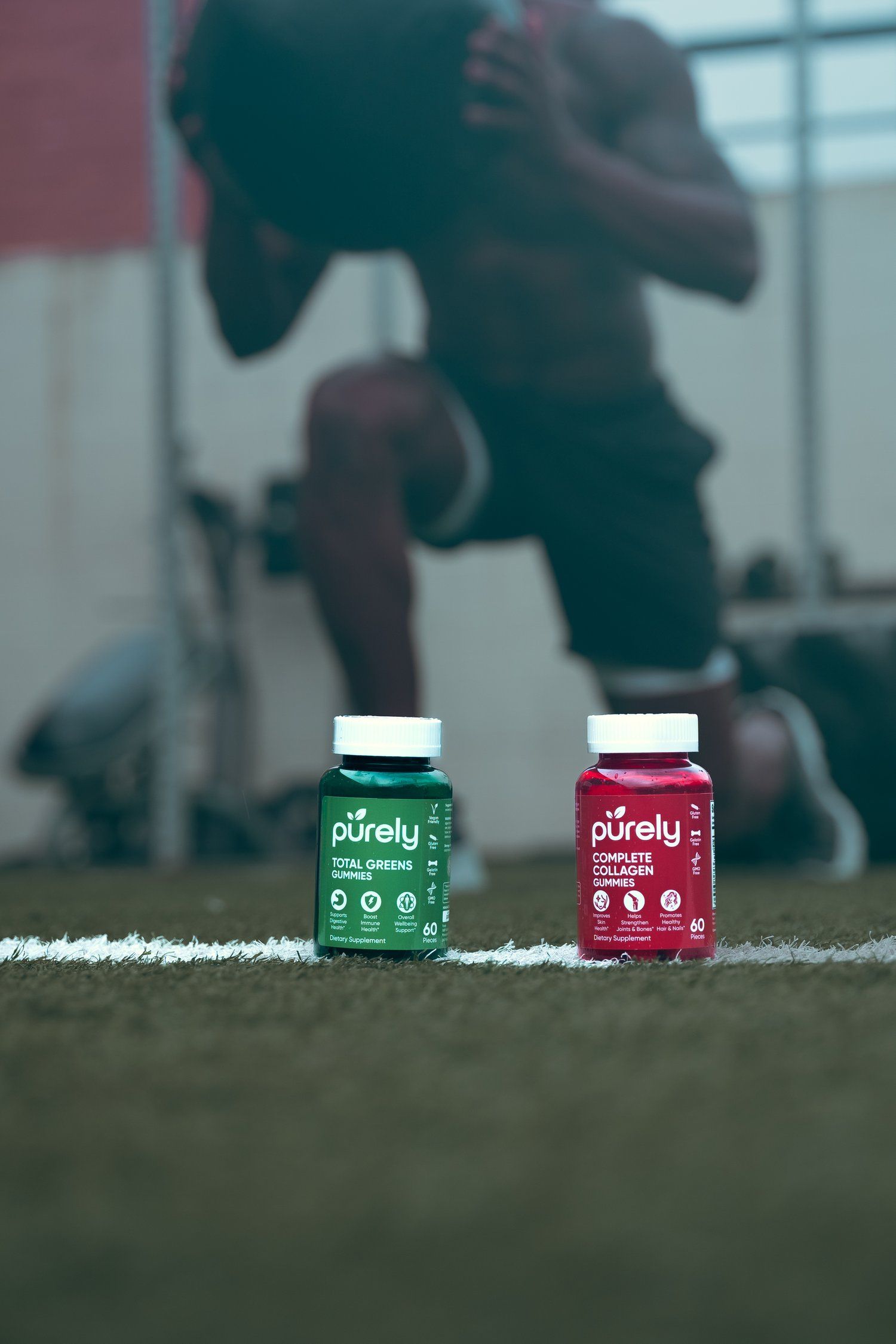 Two supplement bottles on grass field with athletic setting in background.