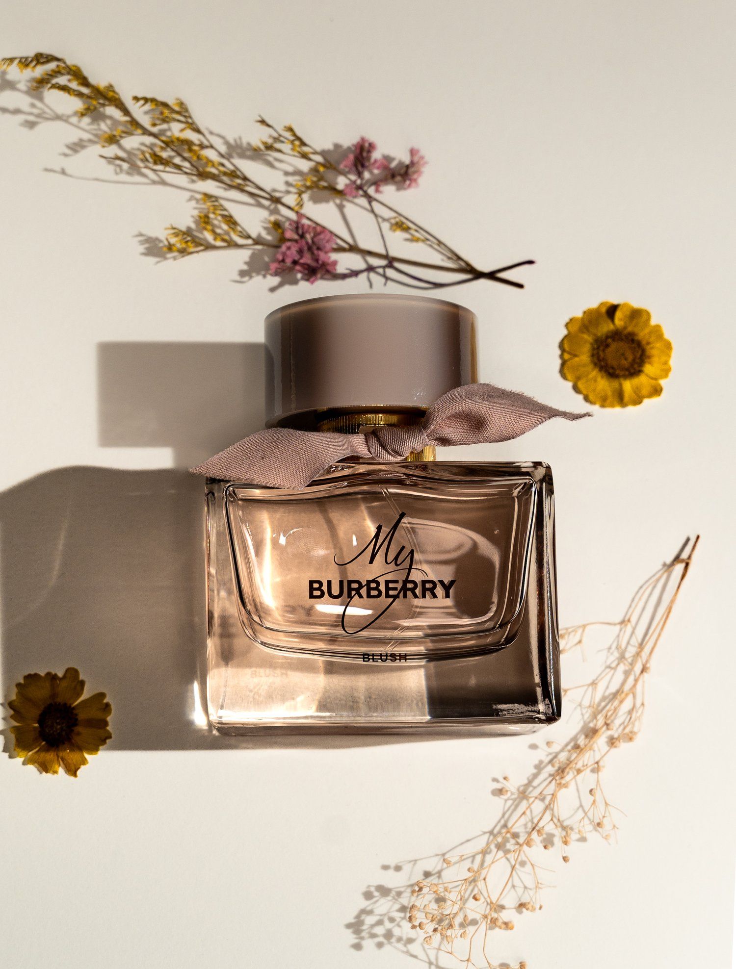 My Burberry perfume bottle styled with dried flowers and sunflowers in soft lighting.