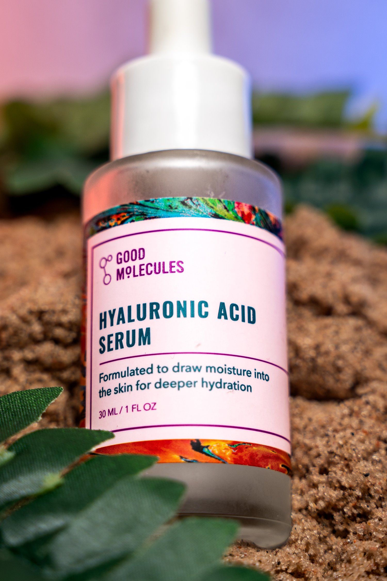 Bottle of Good Molecules Hyaluronic Acid Serum displayed on soil with green leaves.