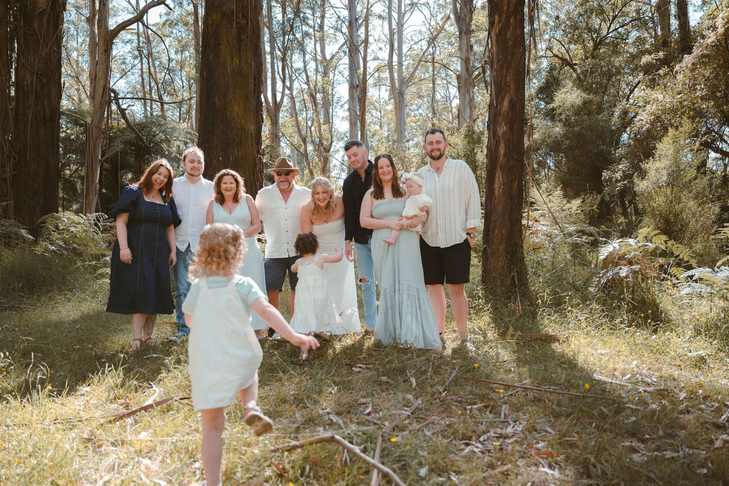 Large group photo of people standing together outdoors among eucalyptus trees.