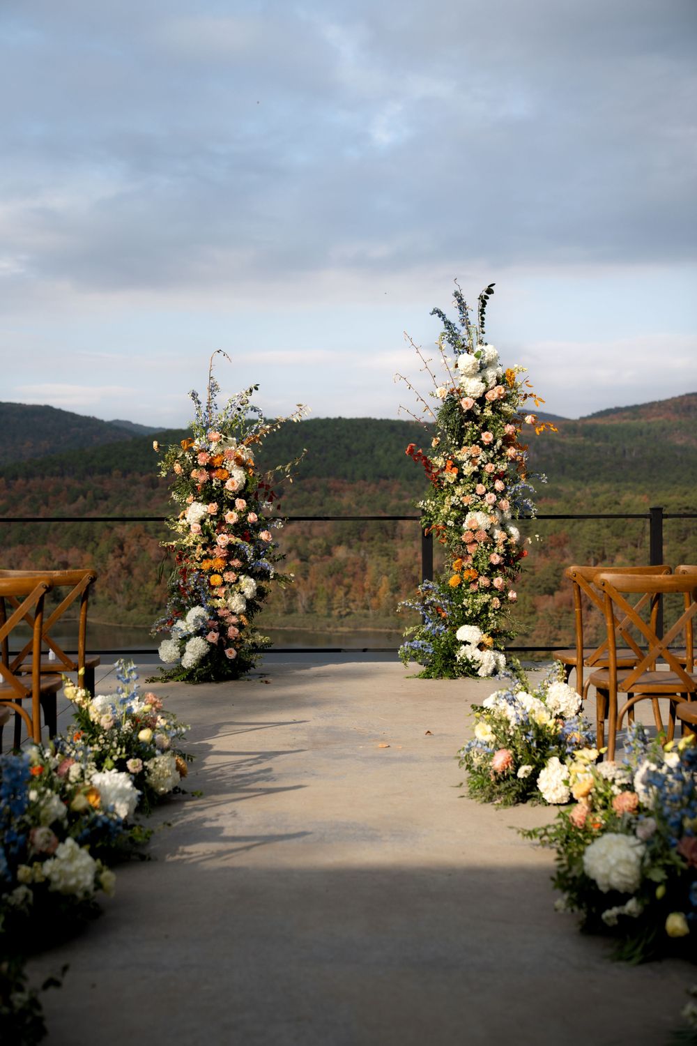 Mountain wedding venue decorated with lush floral arrangements against scenic backdrop.
