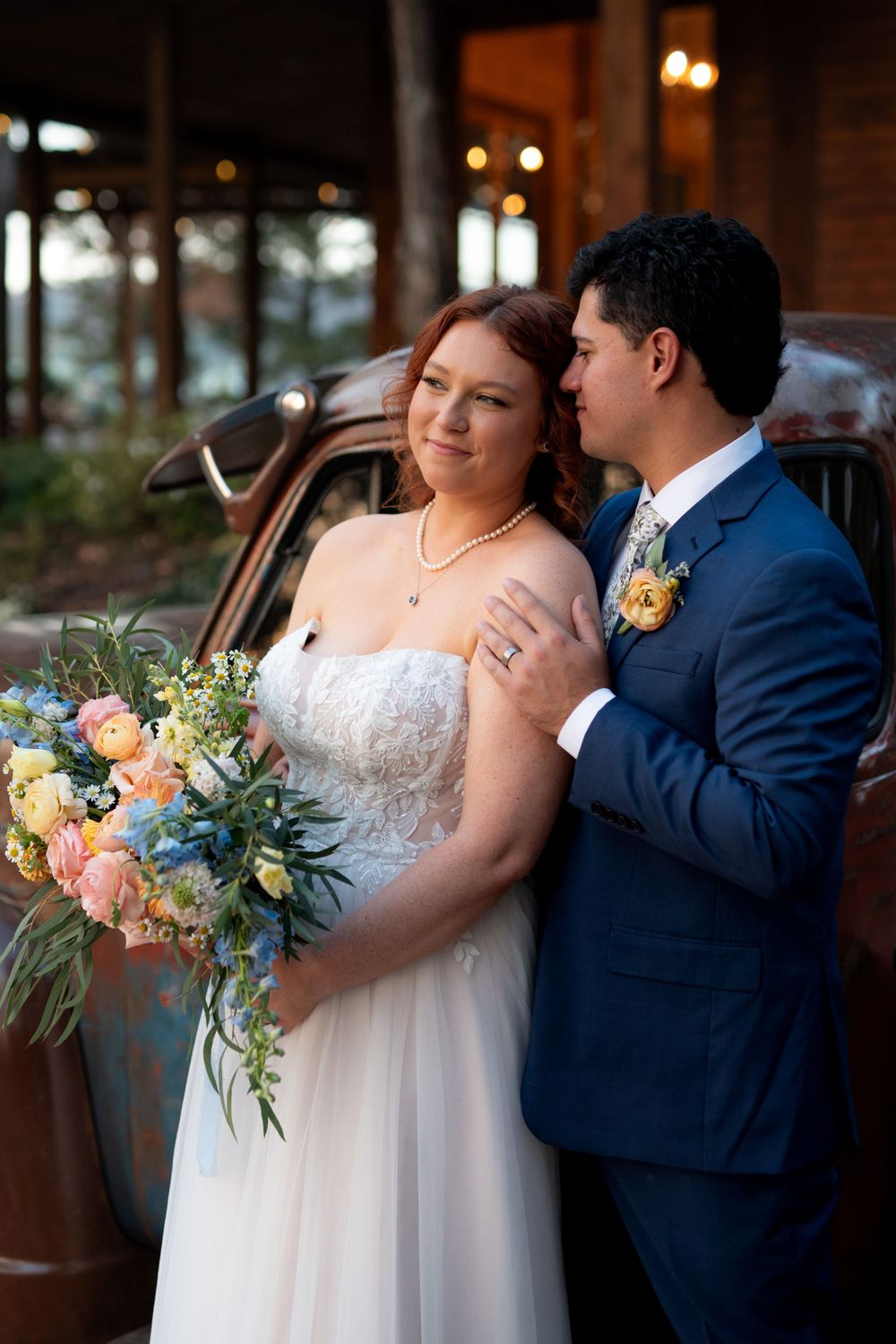 Indoor wedding portrait with elegant floral bouquet in peach and blue tones.
