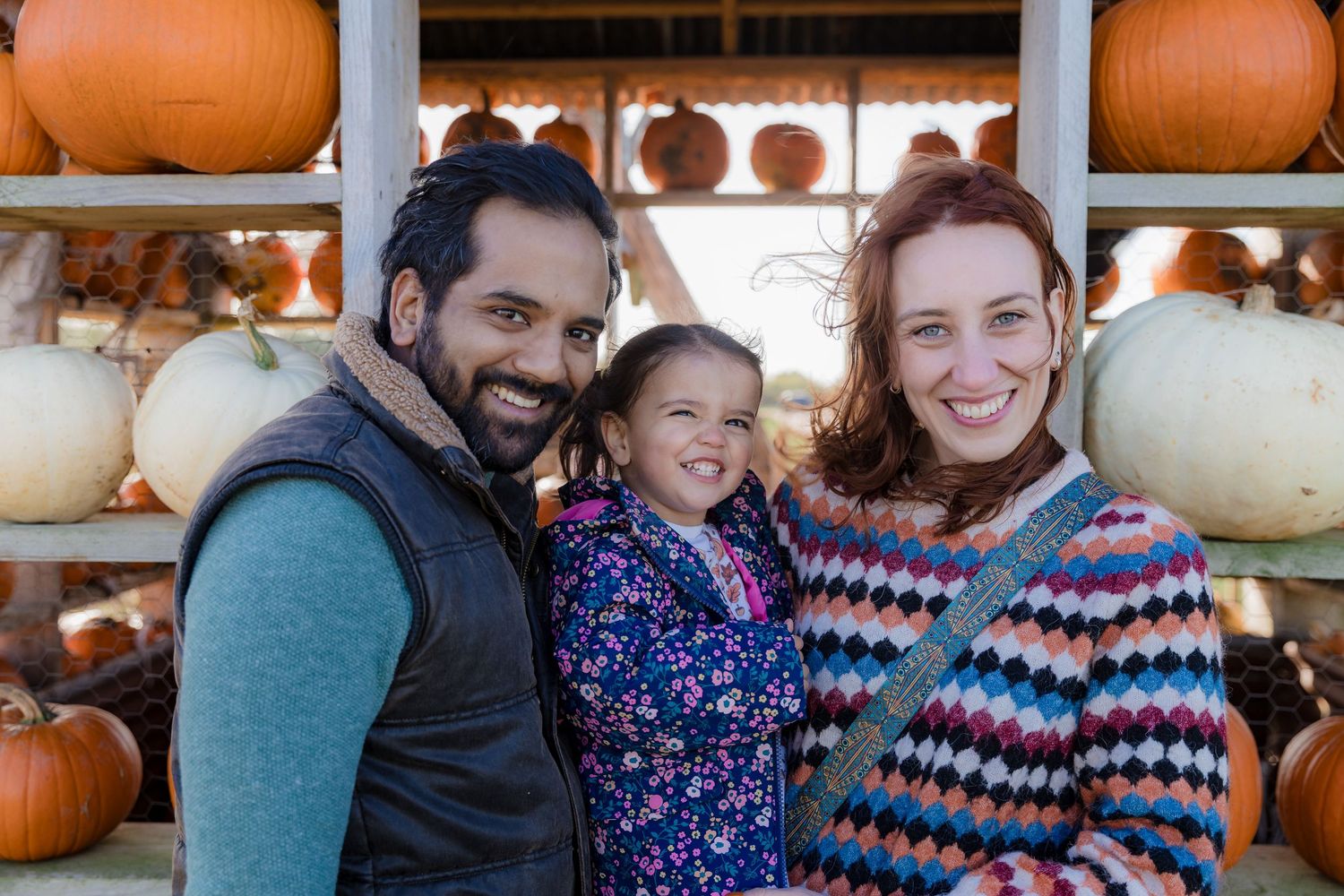Family posing together at pumpkin farm with orange and white gourds in background.  Photographer. Hull. East Yorkshire. Photography
