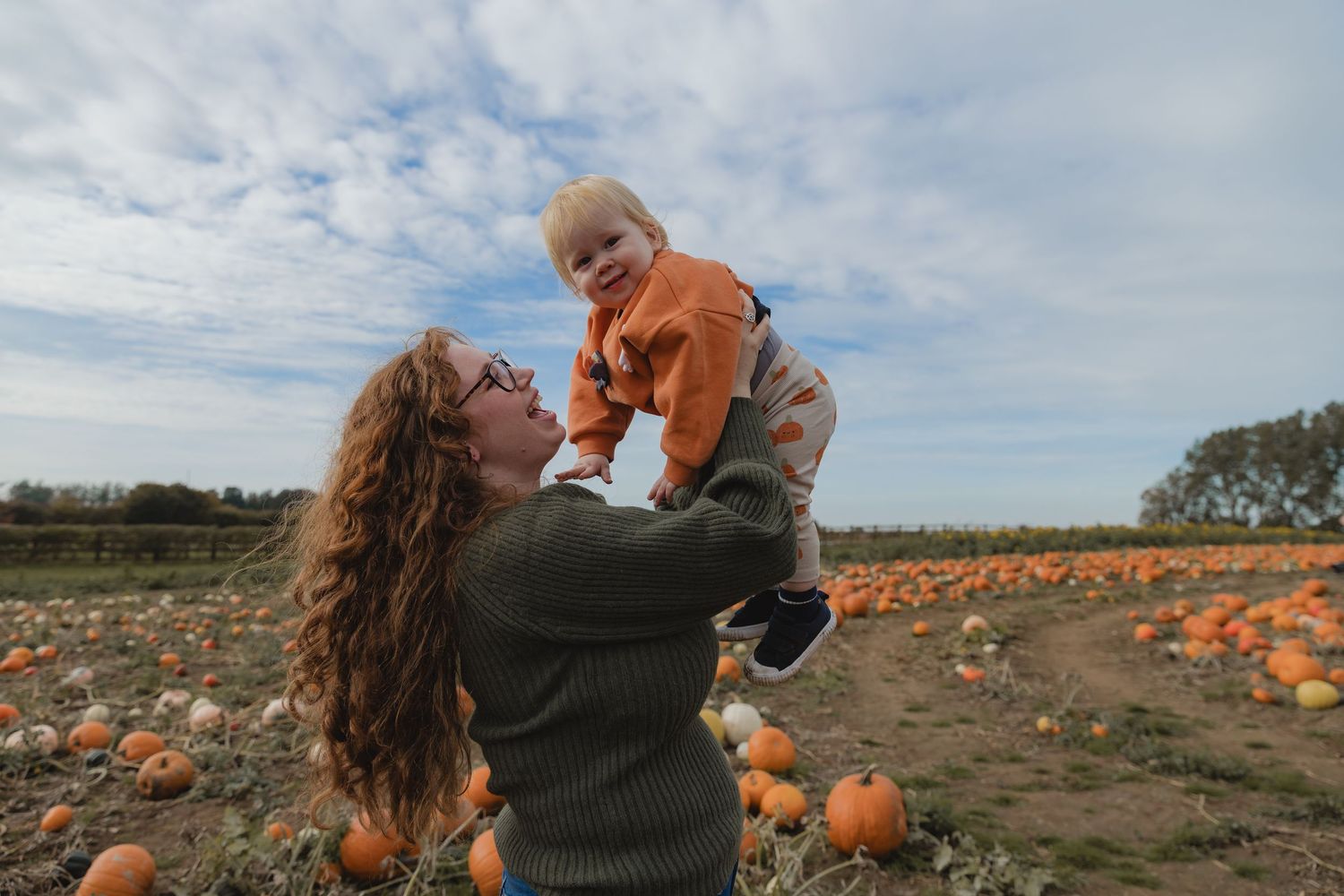 A playful lift against the backdrop of an autumn pumpkin field.  Photographer. Hull. East Yorkshire. Photography