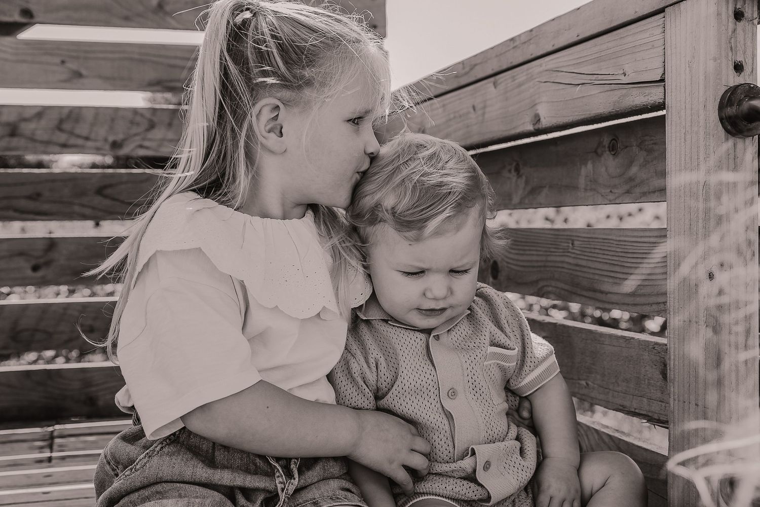 Two children sitting together on wooden steps in a black and white photograph. Photographer. Hull. East Yorkshire. Photography