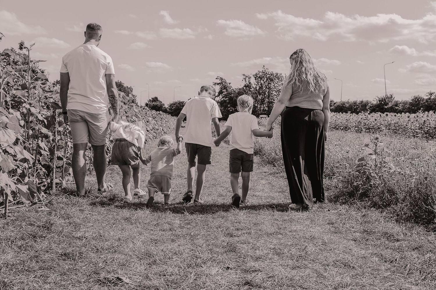 Family walking together through a sunny field holding hands.  Photographer. Hull. East Yorkshire. Photography
