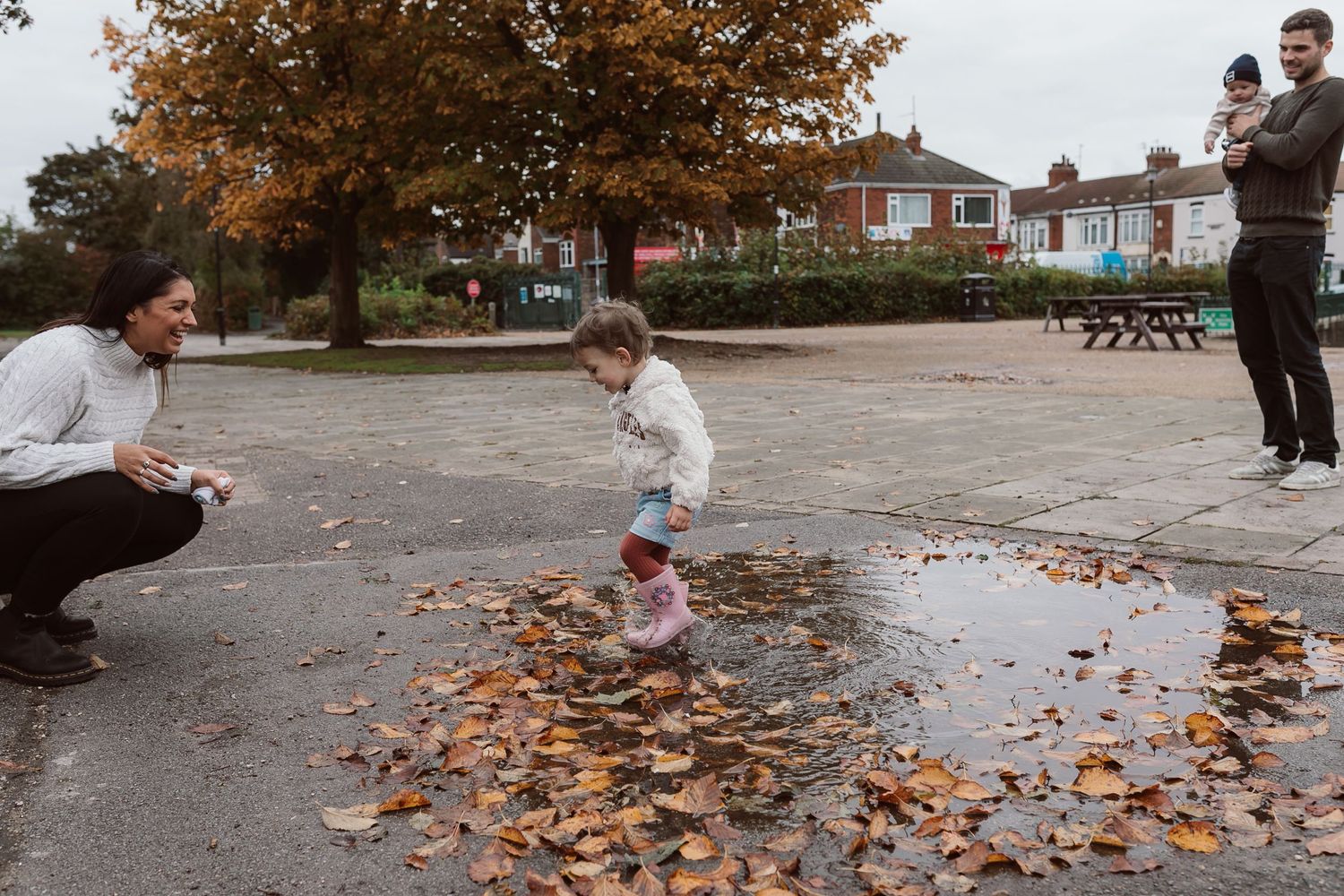 Family walking through scattered autumn leaves in a park on an overcast day. Photographer. Hull. East Yorkshire. Photography
