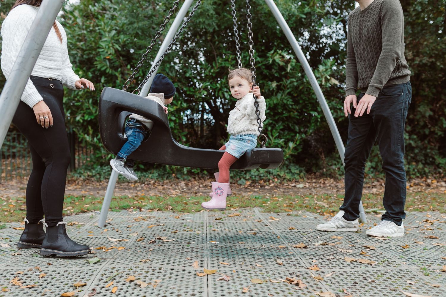 Playful swingset scene at a park with multiple people's feet visible in the frame. Photographer. Hull. East Yorkshire. Photography