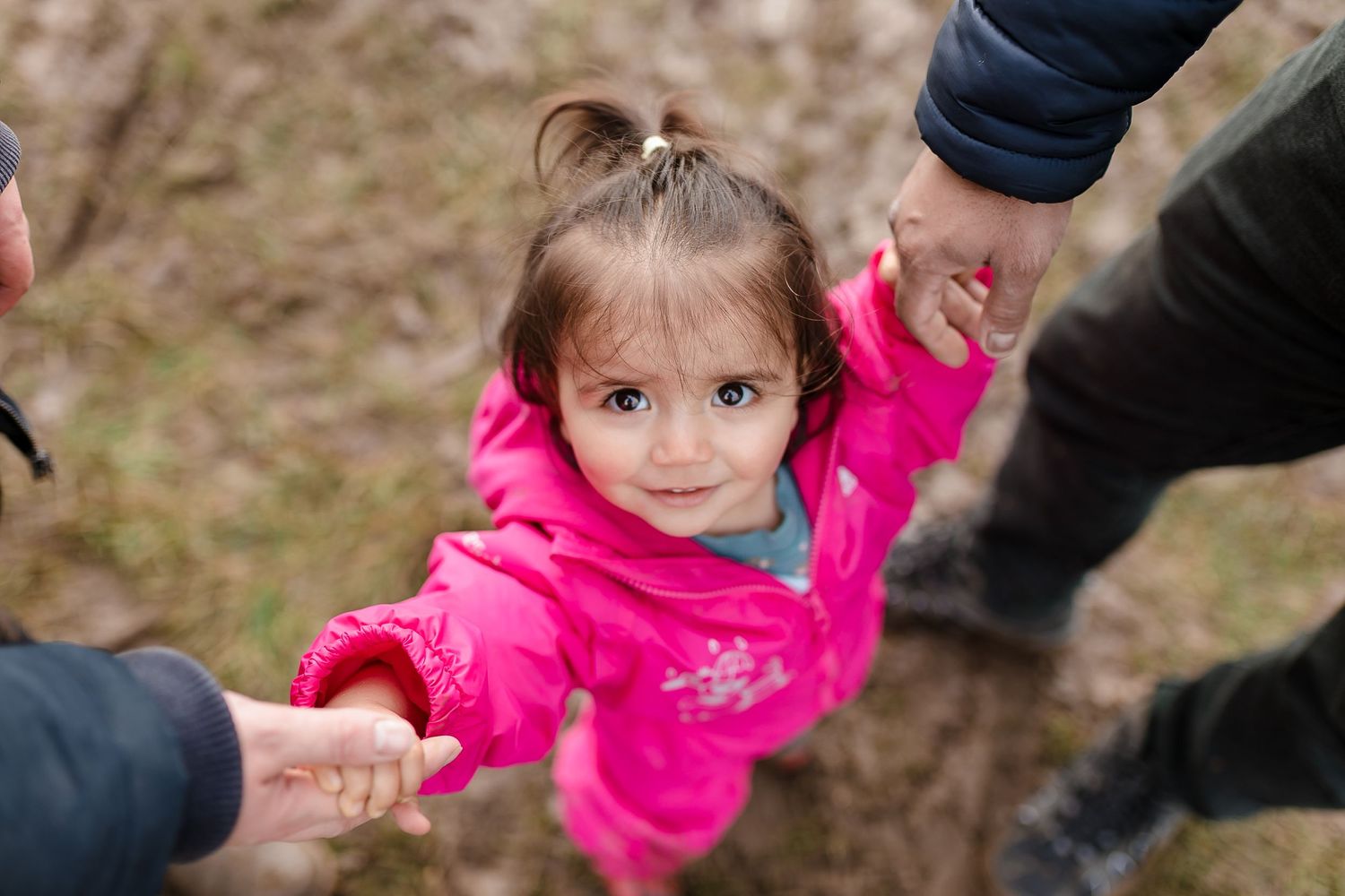 Child in vibrant pink jacket explores muddy pumpkin patch with adult assistance. Photographer. Hull. East Yorkshire. Photography