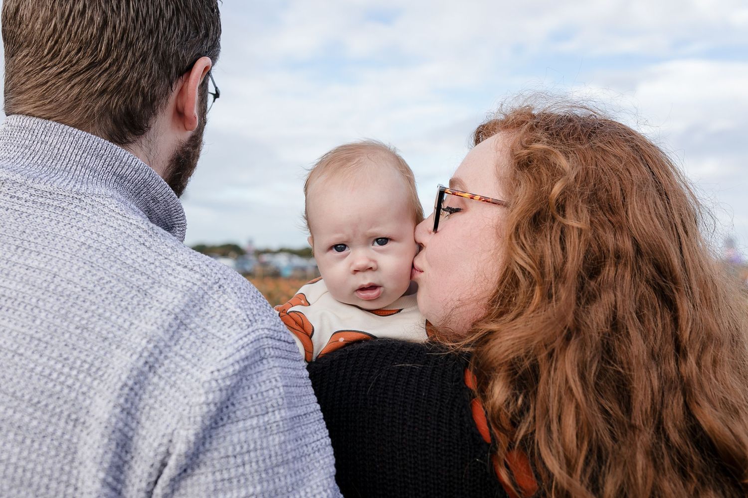 Family members share tender moment together against cloudy sky backdrop. Photographer. Hull. East Yorkshire. Photography