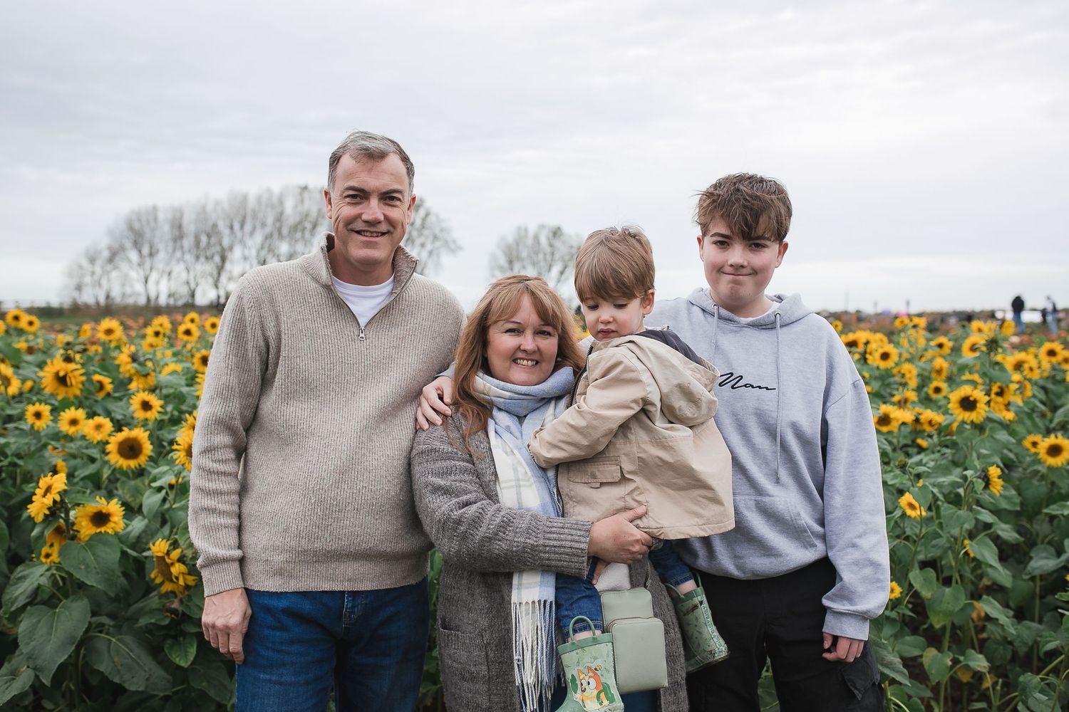 Group enjoying time together in blooming sunflower field under cloudy skies. Photographer. Hull. East Yorkshire. Photography