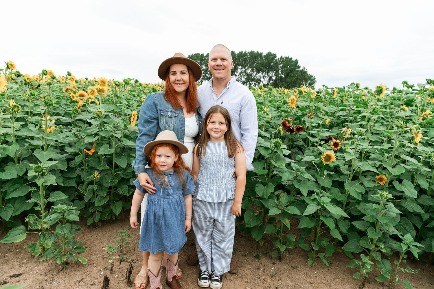 Family posing together in a vibrant sunflower field on a sunny day.  Photographer. Hull. East Yorkshire. Photography