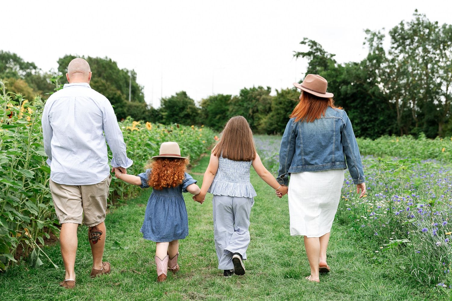 Family walking hand in hand through a wildflower meadow on a summer day.  Photographer. Hull. East Yorkshire. Photography