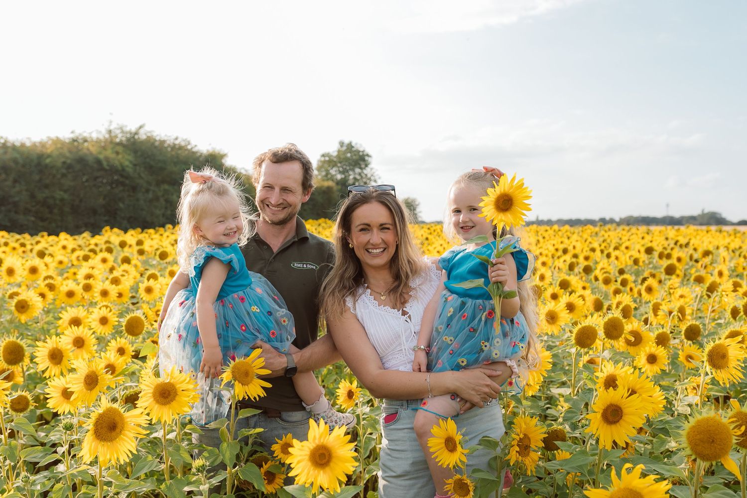 Happy family portrait amidst blooming sunflower field during golden hour. Photographer. Hull. East Yorkshire. Photography