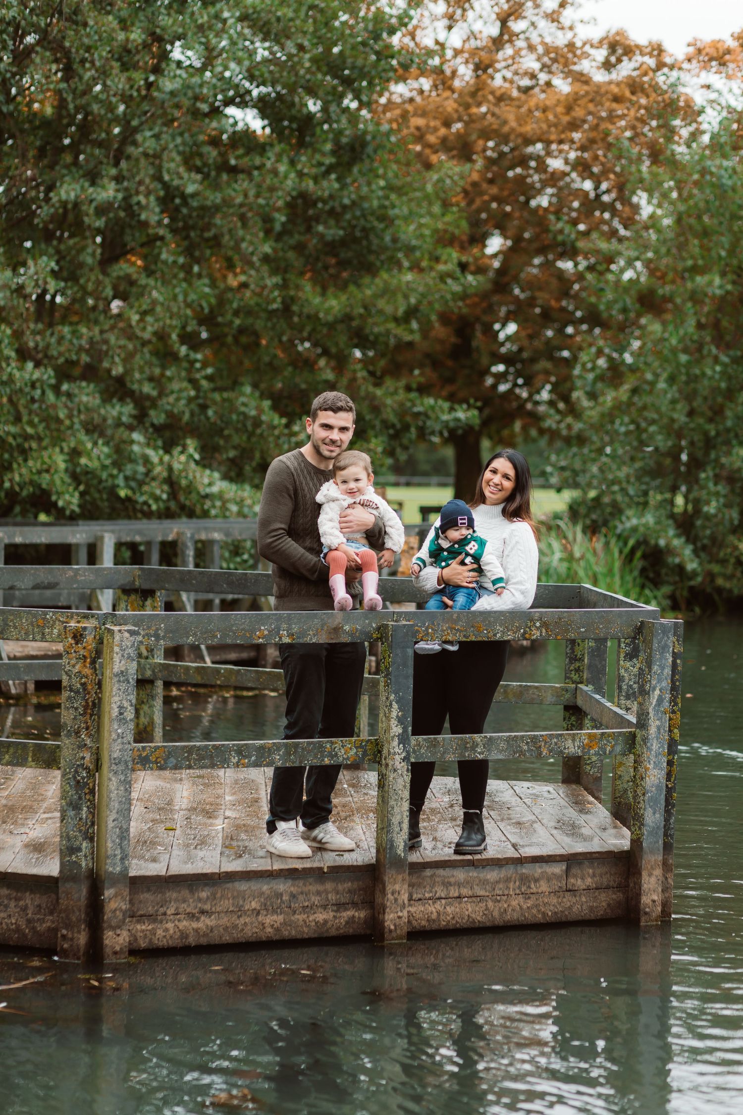Family gathering on a wooden dock overlooking a serene pond surrounded by autumn trees. Photographer. Hull. East Yorkshire. Photography