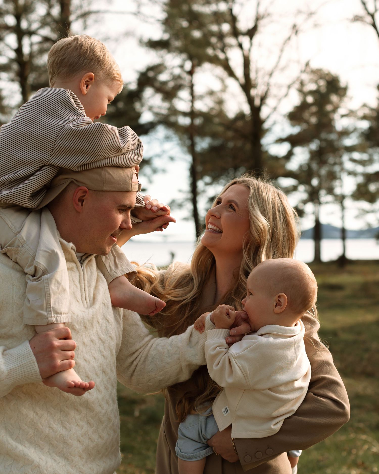 En familie kledd i koselige gensere koser seg sammen i en tåkete høstskog.