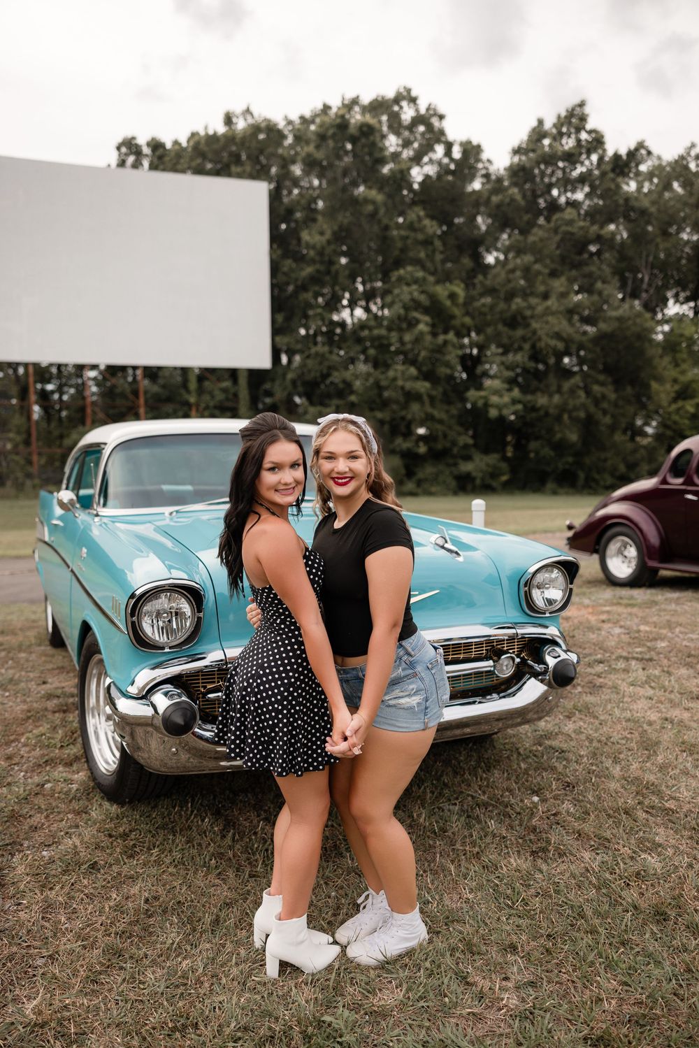 Classic turquoise 1957 Chevrolet car with retro styling parked outdoors in a rural setting.