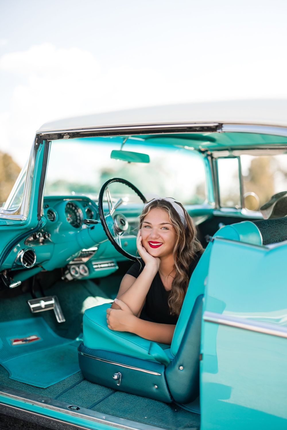 Classic turquoise vintage car interior with teal upholstery and chrome details captured in warm sunlit setting.