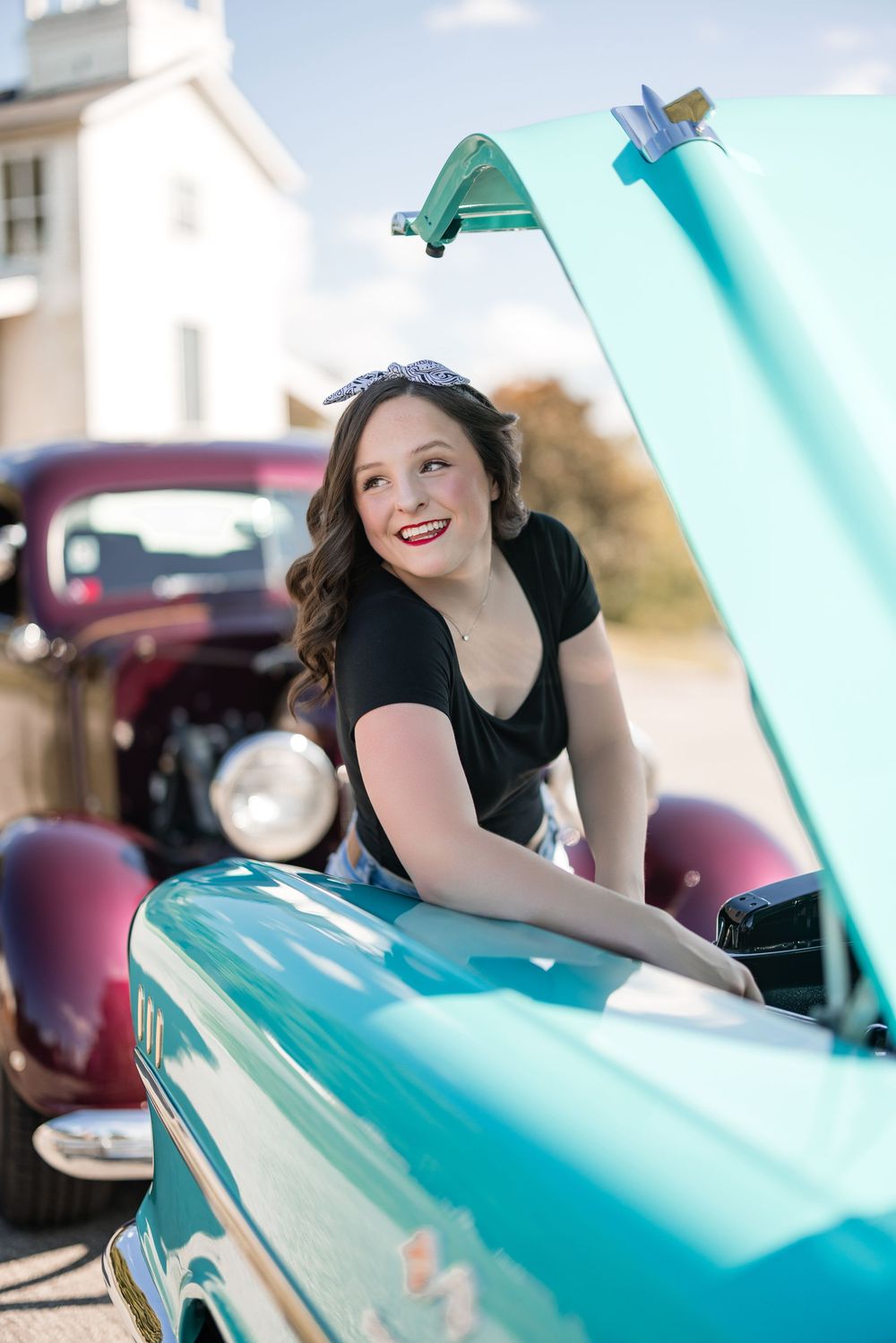 Turquoise vintage Chevrolet with hood up displayed at outdoor car show.