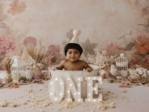 A dreamy nursery scene with white wooden letters and decorative elements arranged against a blush pink background.