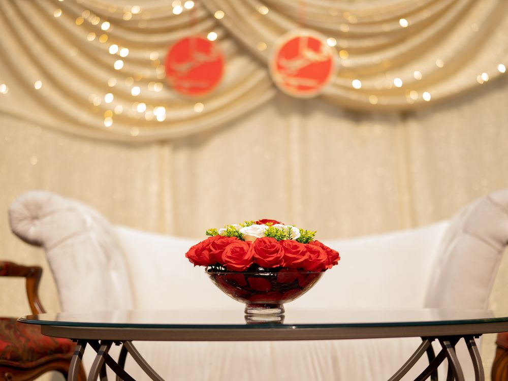 Elegant wedding decor featuring red roses in crystal bowl against cream draped backdrop.