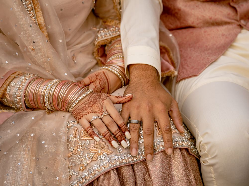 Detail shots of hands with wedding rings and traditional bridal jewelry during ceremony.
