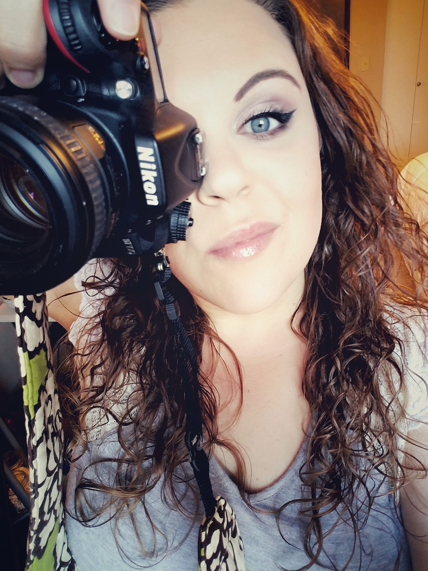 Self portraits with curly dark hair and dramatic makeup next to camera equipment.