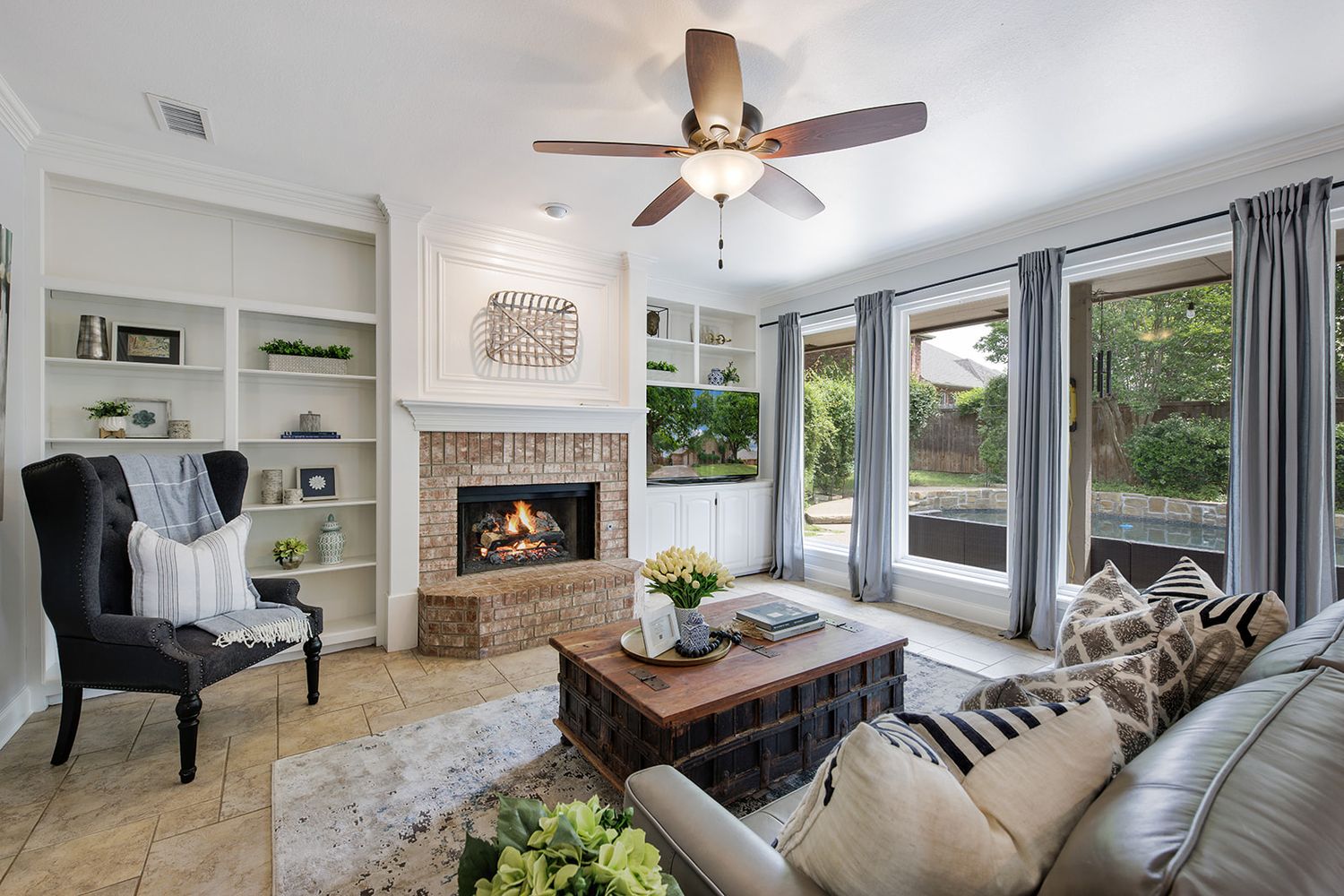 Bright modern living room showcasing a brick fireplace, built-in shelves, and large windows with natural light.