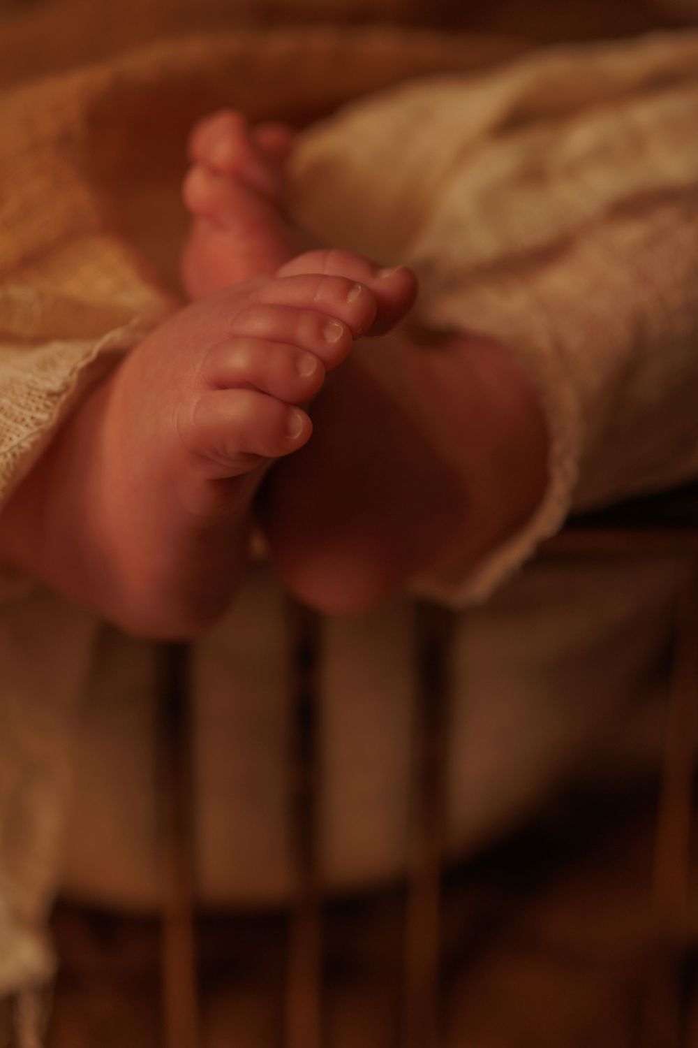 Detail shot of tiny baby feet against cream colored textile.